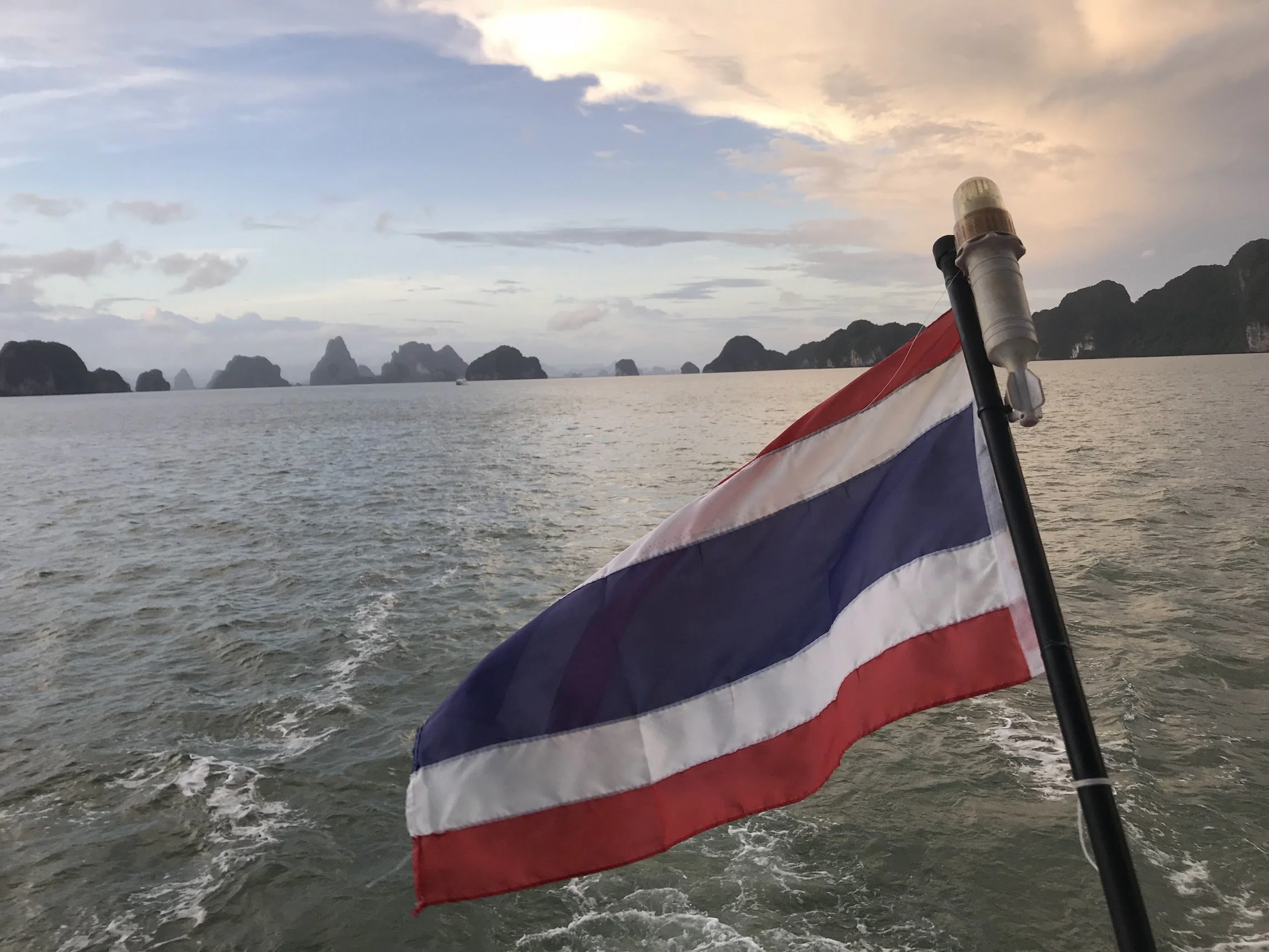 A Thai flag flying from a longtail boat at sea