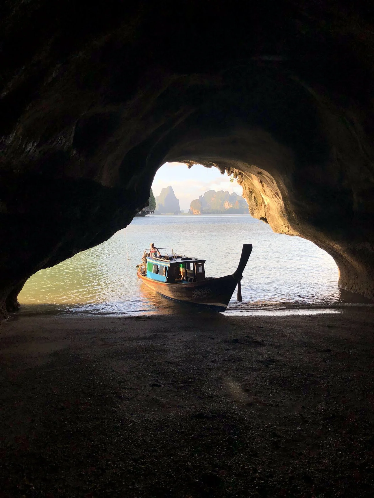 A longtail boat passing into a sea cave