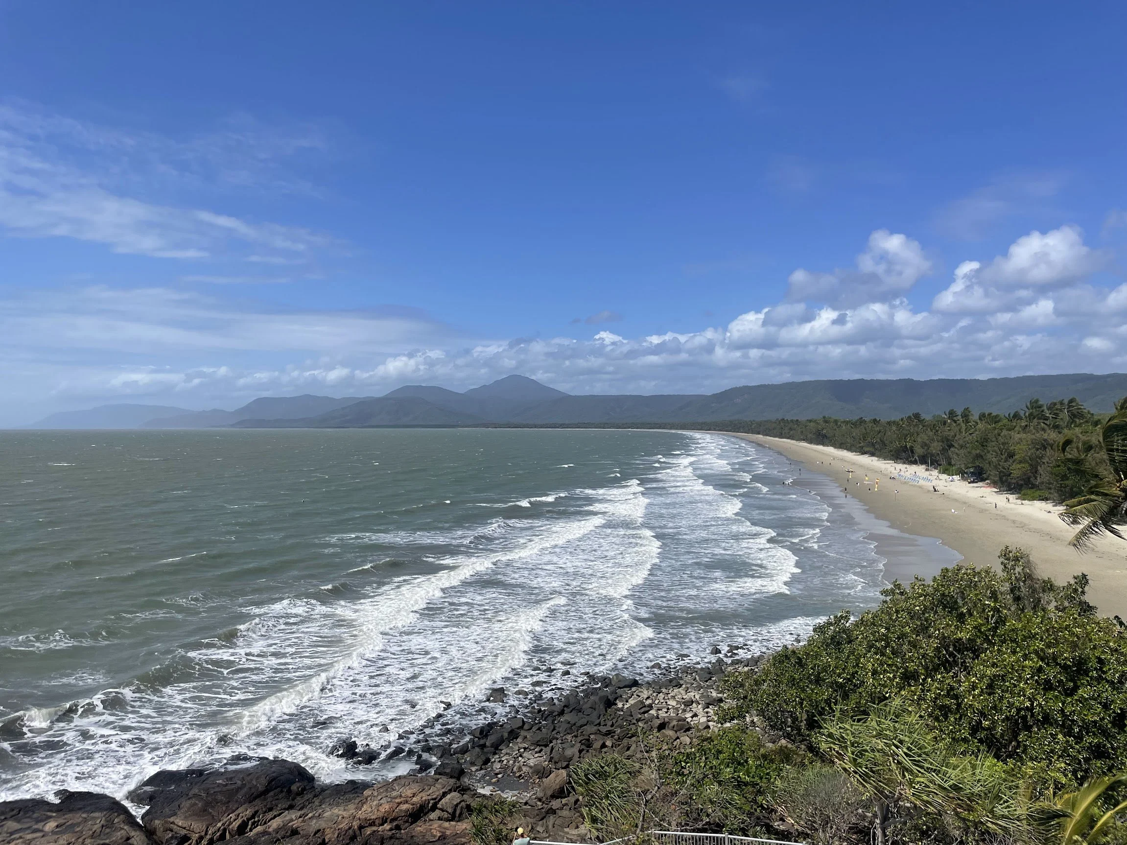 Waves rolling onto Four Mile Beach over dark rocks