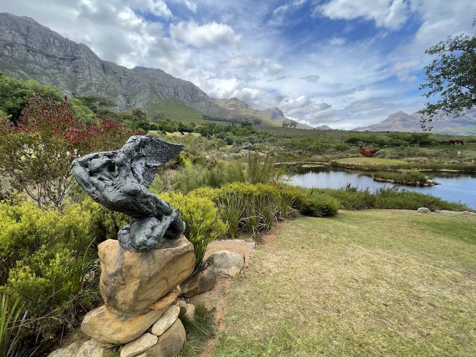 A sculpture set in green gardens below the mountains
